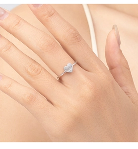 Close-up of a sweet heart-shaped silver ring with zircon stones worn on a finger