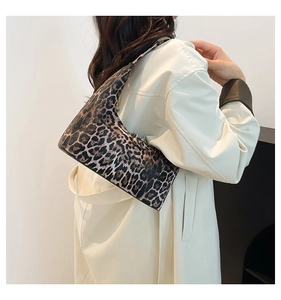 Detailed view of leopard print bucket bag shown with elegant white trench coat outfit