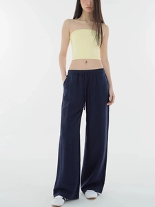 Detail of navy blue wide-leg trousers paired with a pale yellow tube top on a model