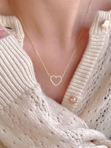 Close-up of a gold heart pendant necklace with shimmering cubic zirconia on a sweater