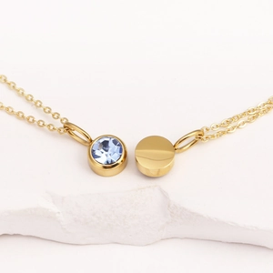 Close-up of golden necklace with light blue gemstone and plain gold disc pendants