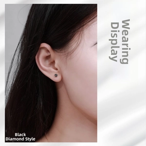 Close-up of a 4-prong black moissanite stud earring worn on a female ear model