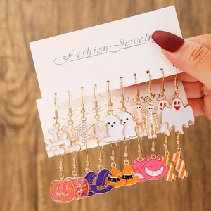 Macro view of assorted Halloween ghost and pumpkin earrings with colorful enamel finish