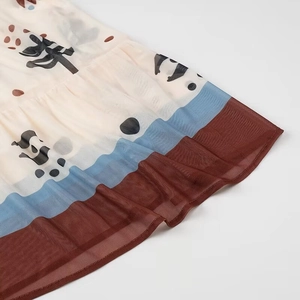 Detail of floral print mesh hem with brown frill and blue stripe on a long dress