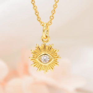 Macro shot of gold sunburst evil eye pendant with sparkling zircon stone detailing