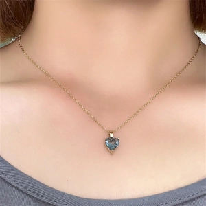 Macro view of blue heart-shaped gemstone pendant on a gold chain necklace for women