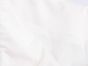 Nahaufnahme der weißen Stoffstruktur mit feiner Webart und weichen, eleganten Falten