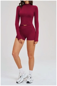 Detail of burgundy fitness set featuring zip-up jacket with thumbholes and cross-waist shorts