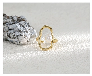 Macro detail of gold adjustable ring featuring oval cutout and center white pearl inlay