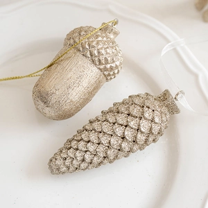 Décorations de Noël glands et pommes de pin champagne doré dans un plat minimaliste blanc
