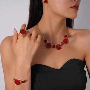 Détail d'une parure de bijoux en émail rouge avec collier et boucles sur un mannequin