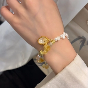 Baroque pearl bracelet with natural yellow crystal and golden charms on a woman's wrist