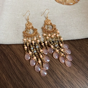Detail of vintage bohemian beaded drop earrings with golden tassels on linen