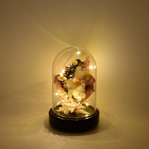 Close-up of preserved flower bouquet with warm LED string lights in a clear dome cover