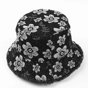 Detail of floral embroidery and frayed edge on a black denim bucket hat for women