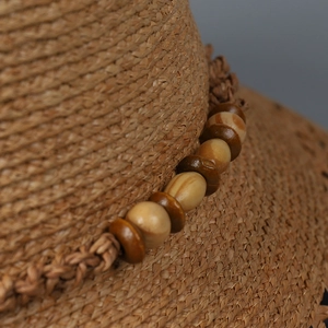 Detailaufnahme der Raffia-Flechtung und dekorativen Holzperlen auf einem Sonnenhut