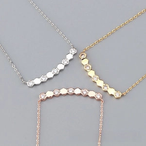 Detail of three hexagonal necklaces in gold, silver, and rose gold with zircon stones