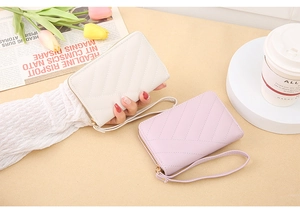 Detail of cream and lilac V-quilted small wallets with wristlets and metal zippers