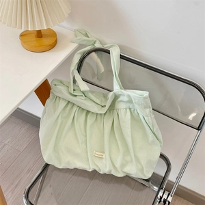 Detailed texture of light green pleated canvas tote with knotted bow shoulder straps