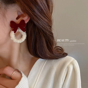Elegant red velvet bow earrings with pearl accents shown on a model for winter style