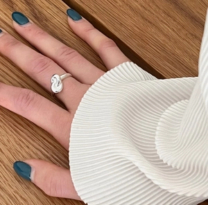 Detail of 925 sterling silver knot ring shown on model against a warm wood background