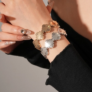 Détail de bracelets trèfles en métal avec gravures florales vintage en or et argent