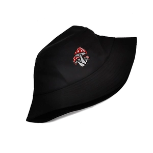 Close-up of three red mushroom embroidery details on a black cotton bucket hat