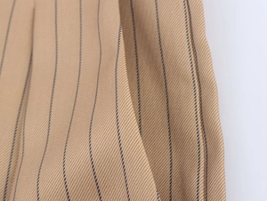 Macro shot of khaki striped linen blend fabric showing detailed twill texture and stitching