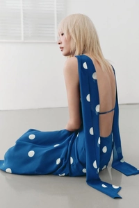 Détail du dos nu d'une robe bleue à pois avec de longs rubans fluides et une coupe ajustée