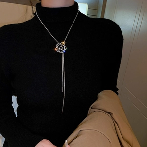 Détail d'un collier camélia argenté avec zircons et longues franges sur un mannequin