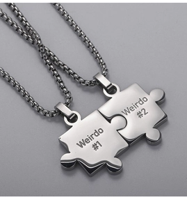 Close-up of interlocking puzzle pendants engraved with Weirdo 1 and Weirdo 2 on silver chains