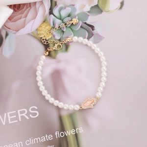 Elegant white pearl bracelet with pink Hamsa hand pendant and adjustable gold chain