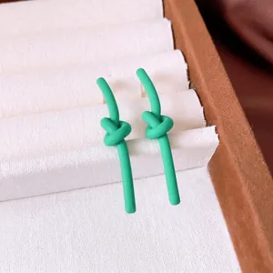 Minimalist matte mint green knotted earrings with silver needle displayed in a box