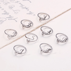 Macro view of silver stainless steel open rings with heart and letter engraving on linen