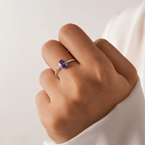 Detail of an oval purple gemstone set in a minimalist silver four-prong ring for women
