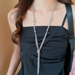 Detail shot of a silver multi-layer tassel necklace on a model with metallic beads