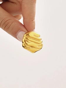 Macro detail of gold geometric earrings with liquid ripple texture on metal surface