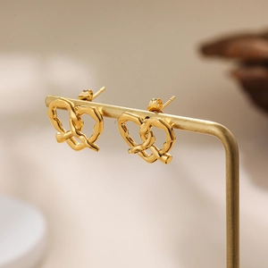 Detailed view of 18K gold-plated stainless steel knot earrings on a golden stand