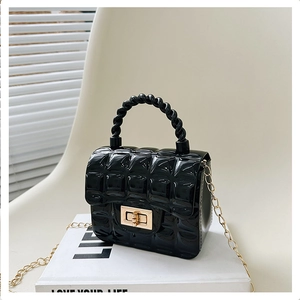 Detail of black quilted jelly bag with golden twist lock on minimalist white book background