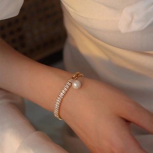 Gros plan détaillé d'un bracelet vintage doré orné de zircons et d'une perle blanche