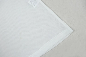 Close-up of white mesh fabric texture and size L label on long sleeve bodycon dress