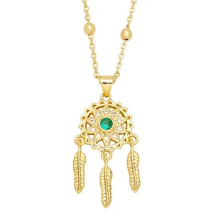 Golden dreamcatcher necklace with emerald green stone and feather pendants on white backdrop