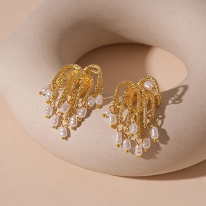 Macro shot of gold textured metal earrings with fireworks fringe and white pearls