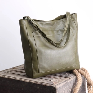 Détail du grand sac cabas vintage en cuir vert olive sur boîte en bois avec corde rustique