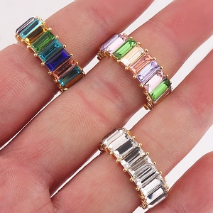 Gold-plated eternity rings with baguette-cut colorful crystals on a hand model