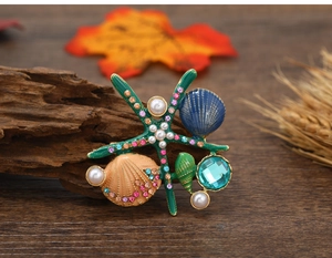 Detailed view of colorful enamel starfish and seashell brooch with pearls and rhinestones