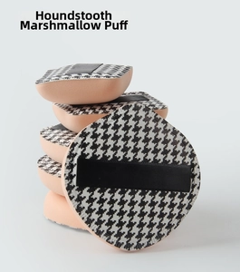 Macro detail of thick houndstooth pattern makeup puffs with black satin ribbon handles