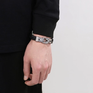 Detail of men's black woven leather bracelet with polished silver metal G-shaped clasp