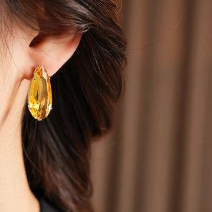 Close-up of elegant yellow teardrop gemstone earrings on model with metal base