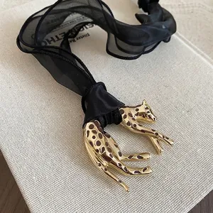 Luxury leopard pendant necklace with golden finish and black fabric ribbon on book